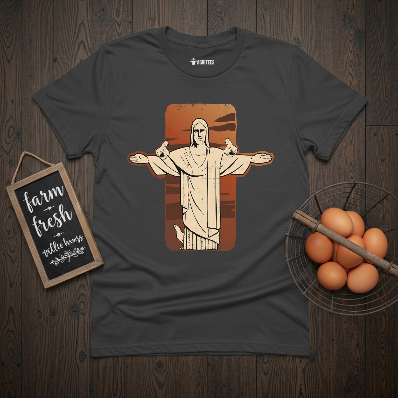 T-shirt featuring stylized illustration of the Christ the Redeemer statue from Rio de Janeiro with chickens perched on its outstretched arms, set against a rust-colored background on grey fabric, blending iconic landmark imagery with chicken keeping themes.