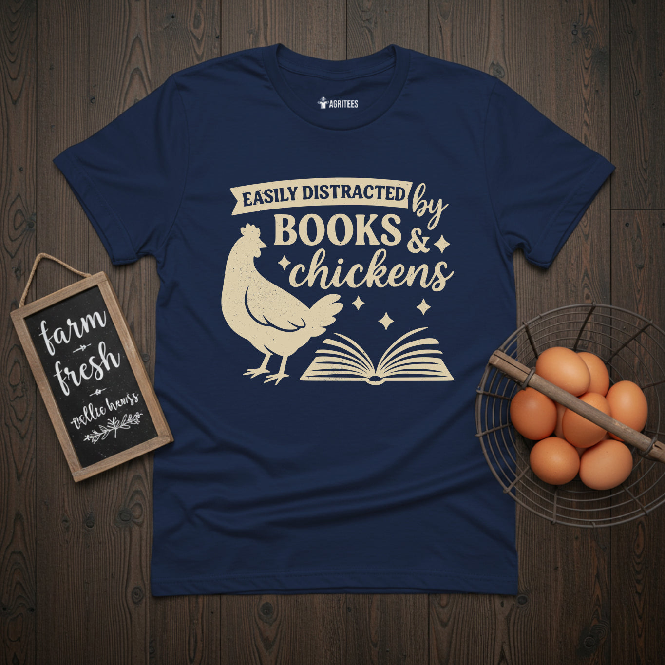 Navy blue t-shirt with vintage cream illustration showing a chicken beside an open book and text reading 'Easily Distracted by Books & Chickens' - ideal gift for readers who also enjoy backyard chicken keeping.